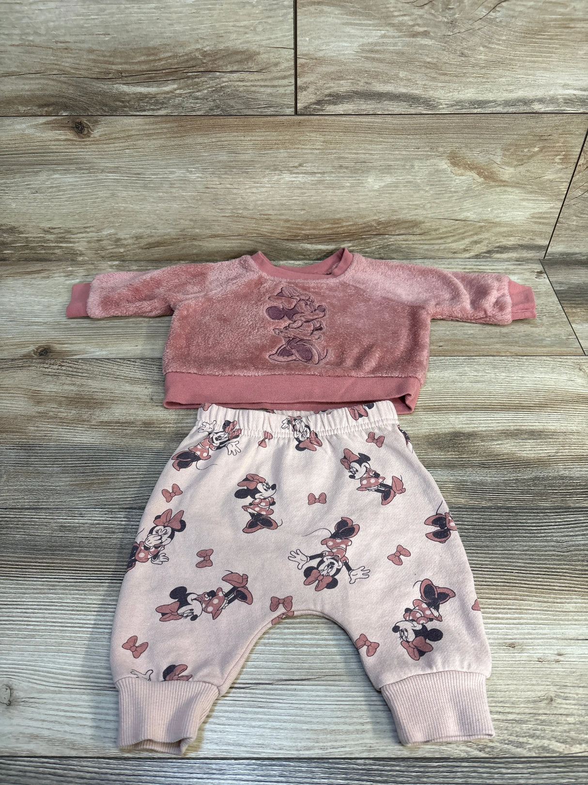 Pink baby outfit set with Minnie Mouse sweatshirt and matching pants on wood background
