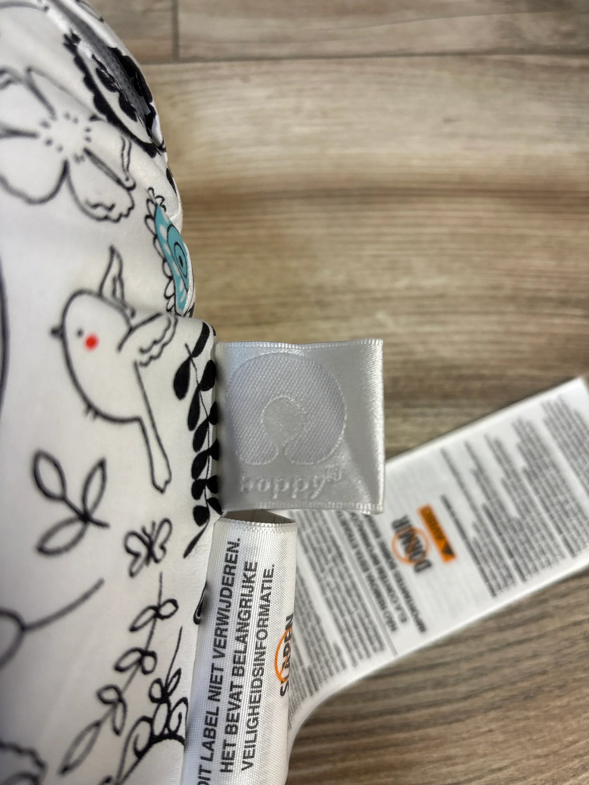Close-up of Boppy nursing pillow Doodles slipcover showing bird and flower doodle print with teal accent and care tags