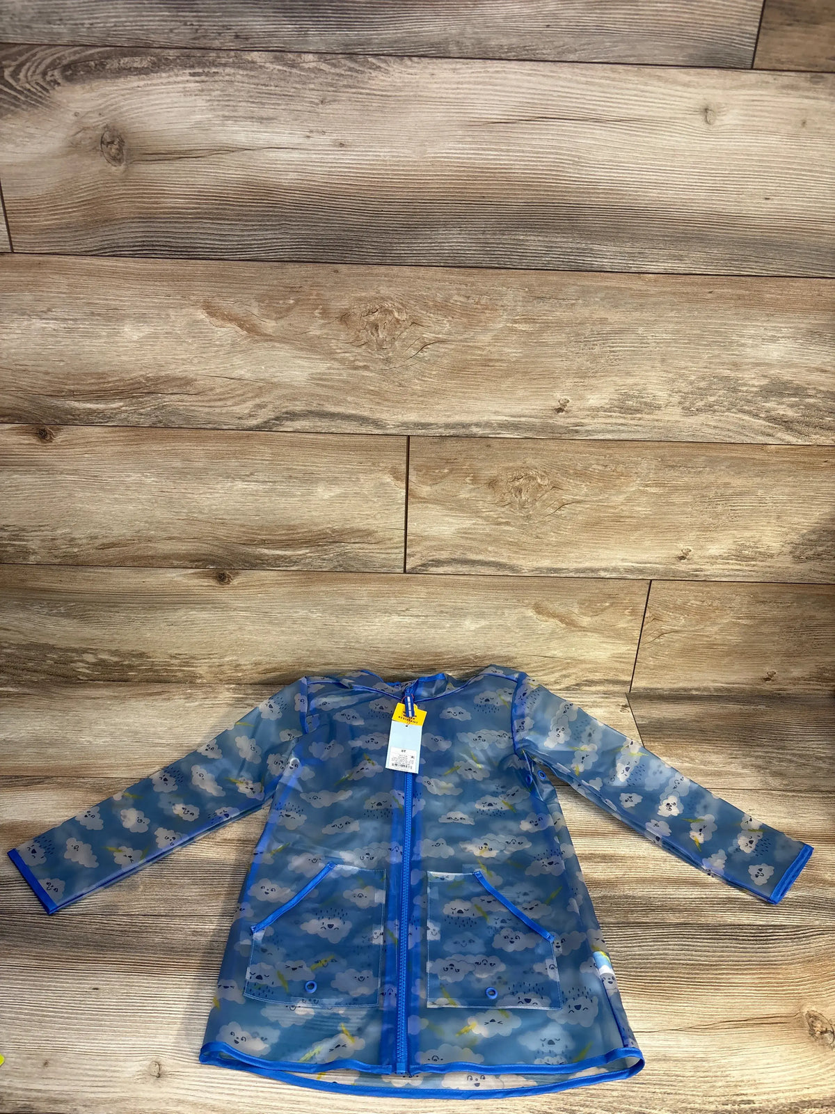 Front view of Cat and Jack blue clear cloud printed rain jacket size 5T showing zip closure and front pockets on wood flooring
