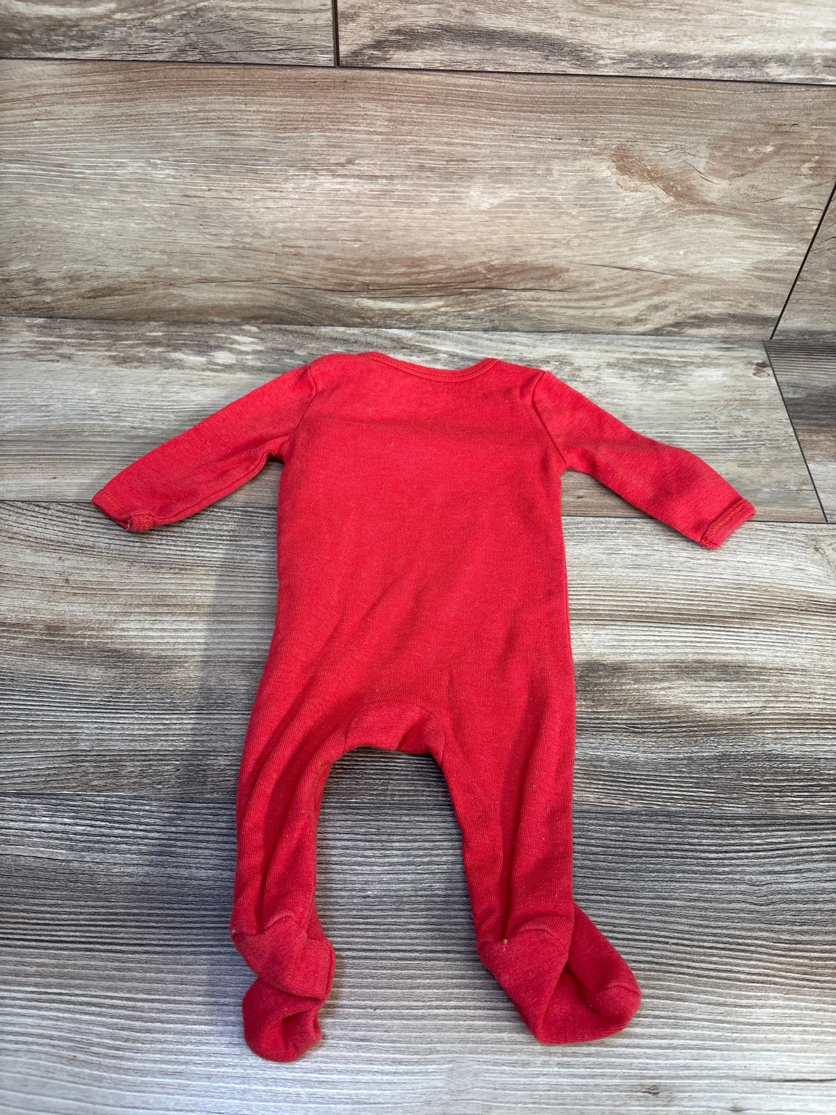 Back view of Flash Can’t Catch Me sleeper showcasing red long sleeves and attached footies on a wood-look background