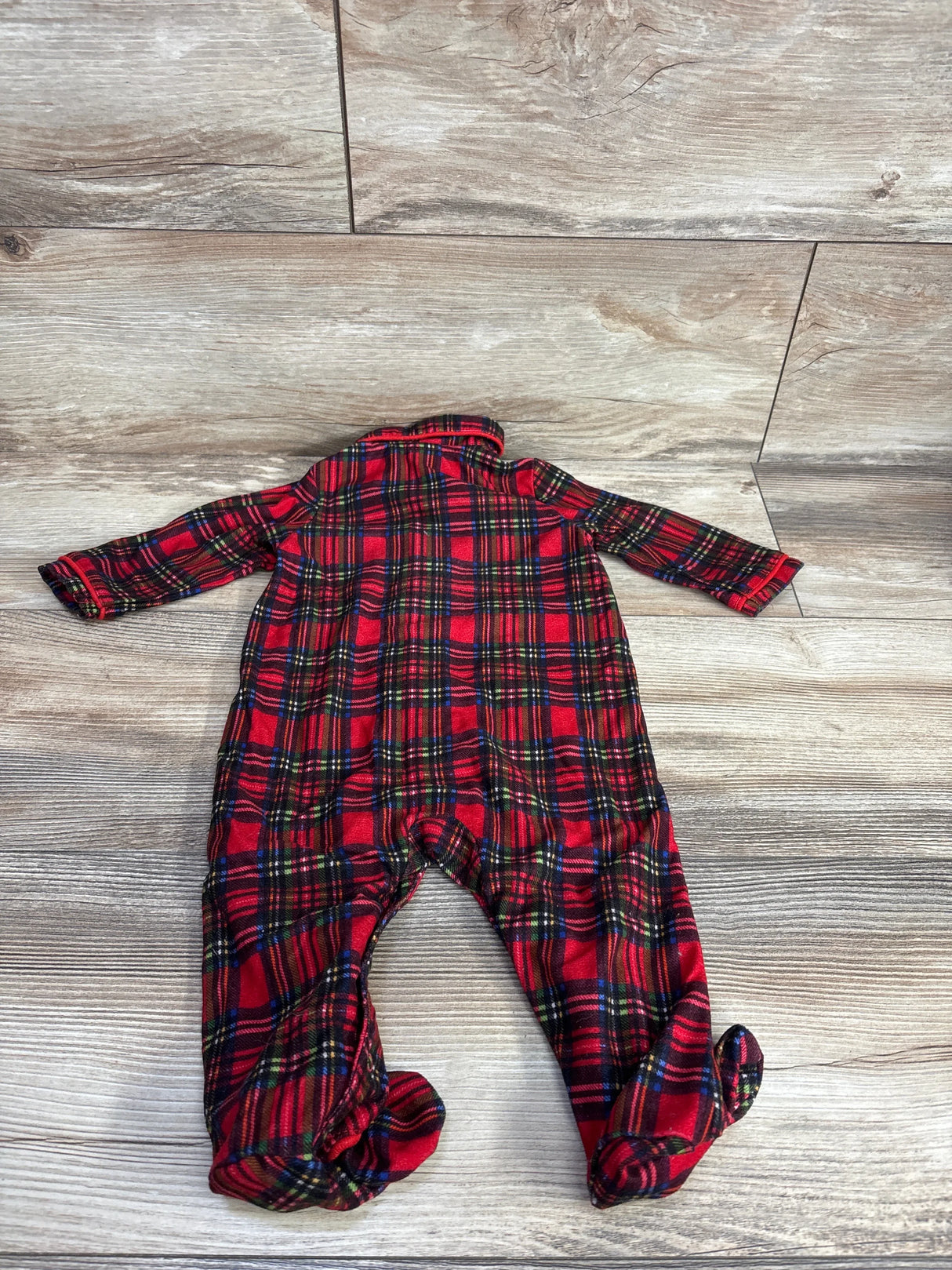 Red plaid baby sleeper footed pajamas on wood background