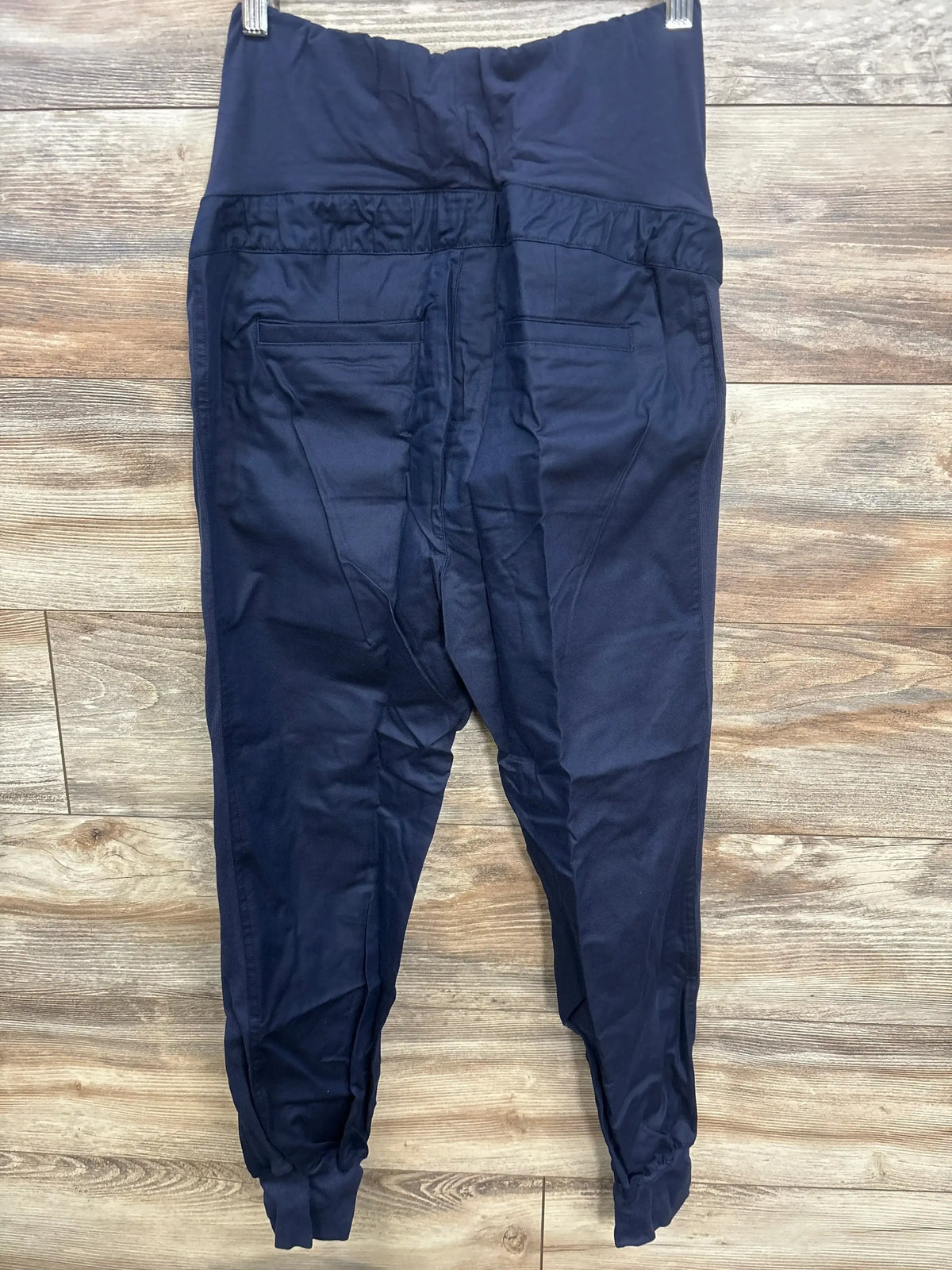 Front view of navy maternity joggers showcasing full-panel elasticized waistband and elasticized hems on a wood floor