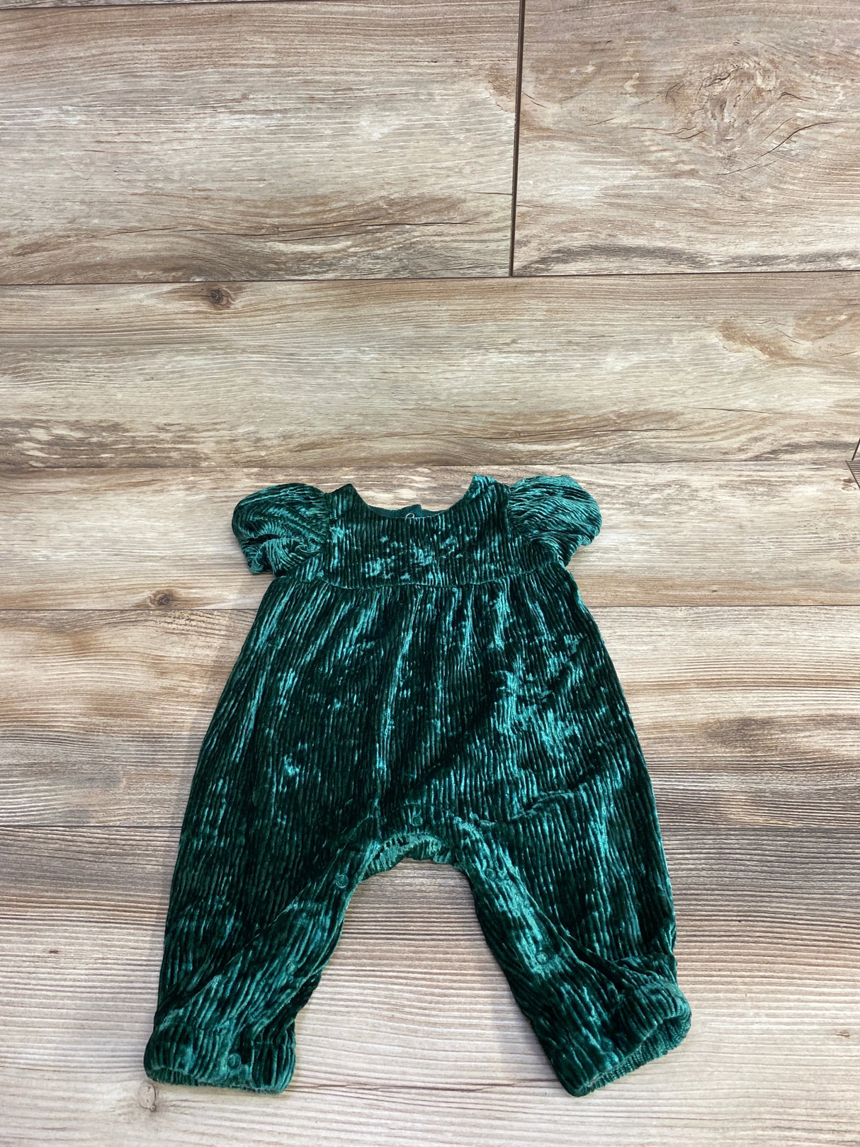 Green velvet baby romper with short puff sleeves on wooden floor, kids clothes resale