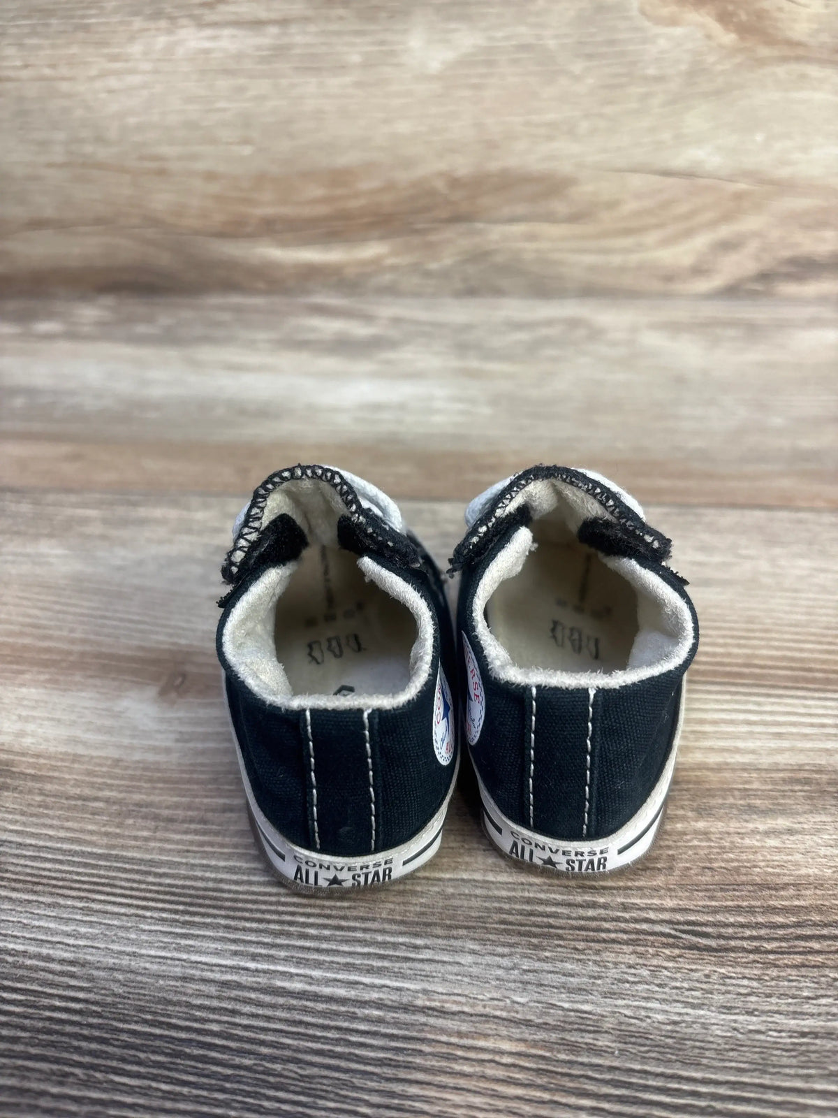 Rear view of black Converse All Star Cribster Easy-On Shoes, size 1C, showcasing soft outsoles and terry cloth lining on wood