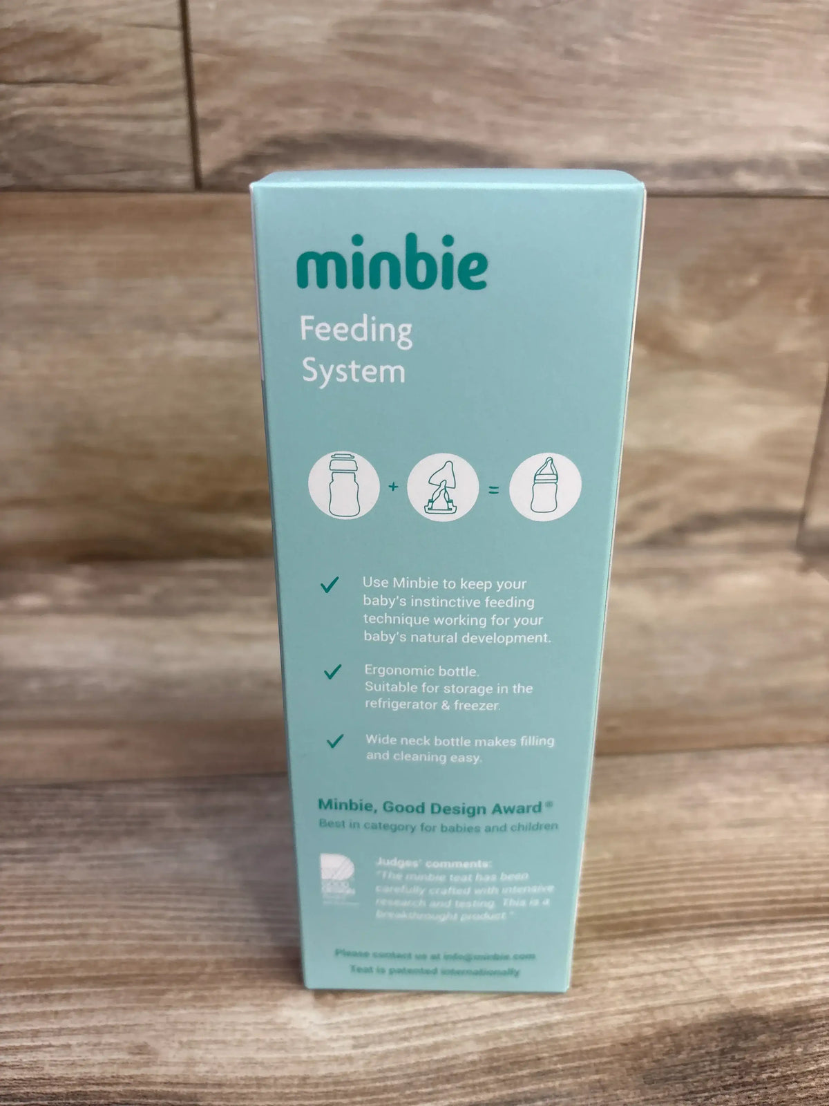 Front view of Minbie 6m+ Feeding Kit box with minbie Feeding System branding and feature bullets on a wooden tabletop