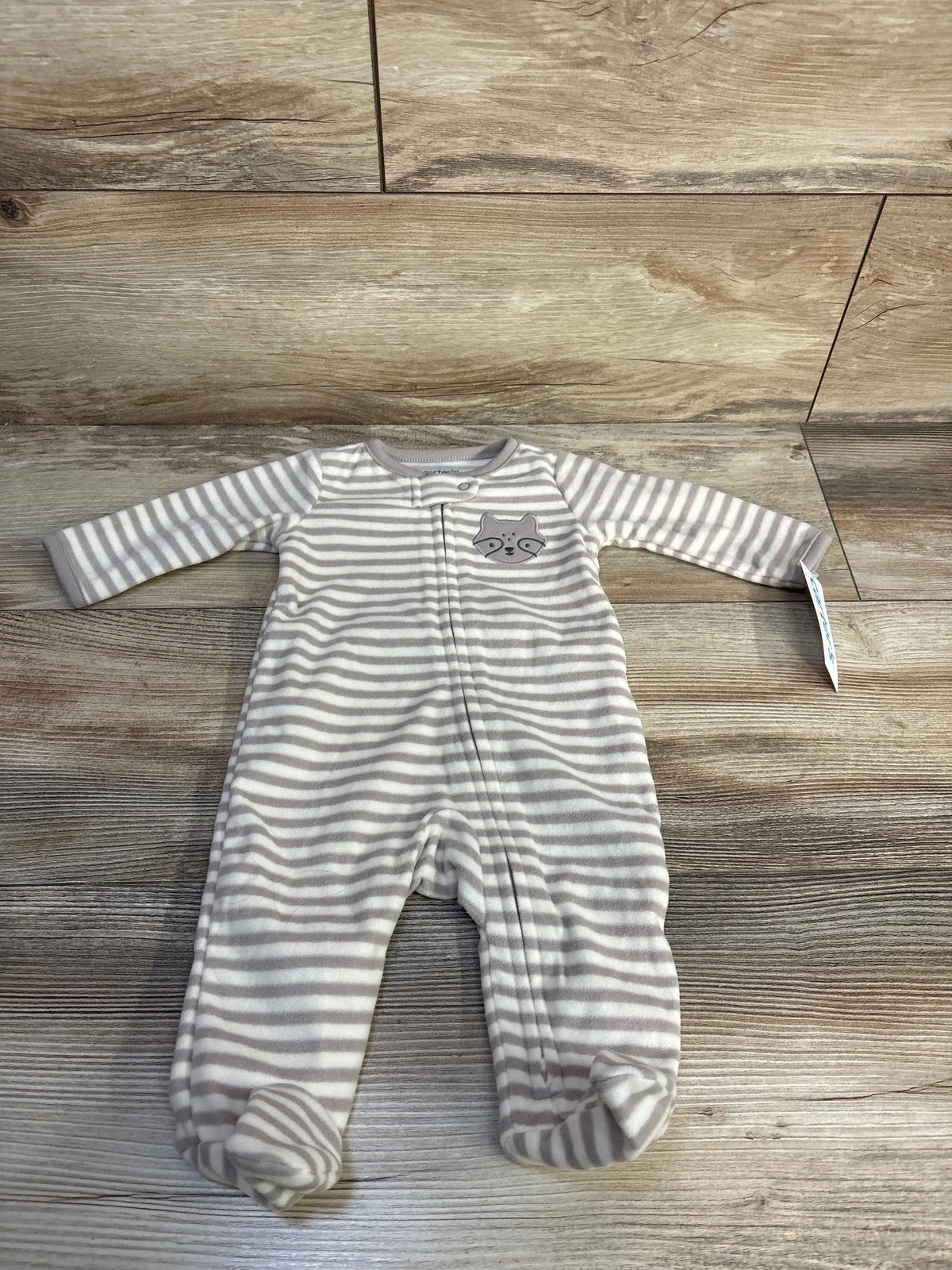 Front view of Carters beige striped blanket sleeper showcasing enclosed feet with a wood look floor background