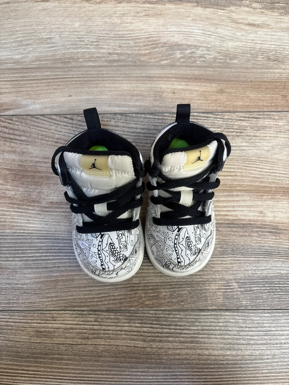 Top view of Air Jordan 1 Mid SE TD 'DIY' toddler sneakers size 4C showing black laces, black-and-white graphic upper and Jumpman logo on wood floor