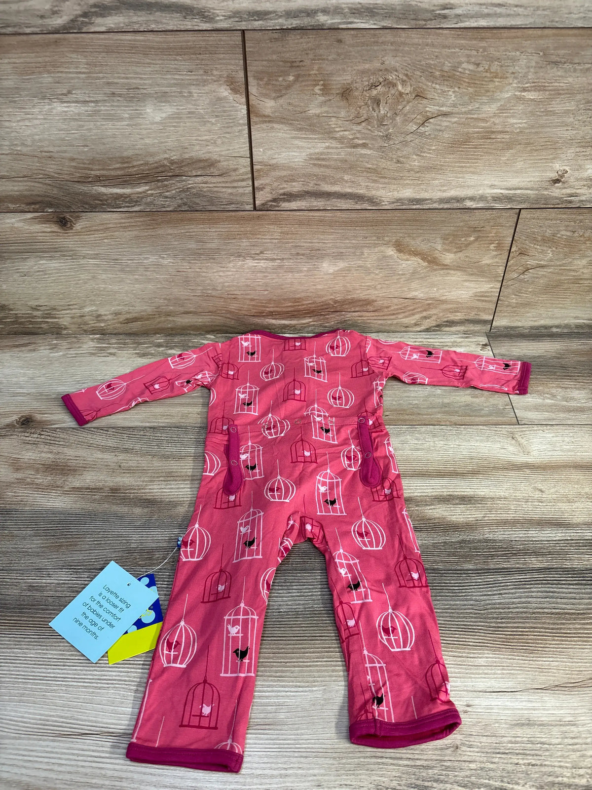 Front view of KicKee Pants coverall showcasing Winter Rose Birdcage Pink print and long sleeves on a wood floor