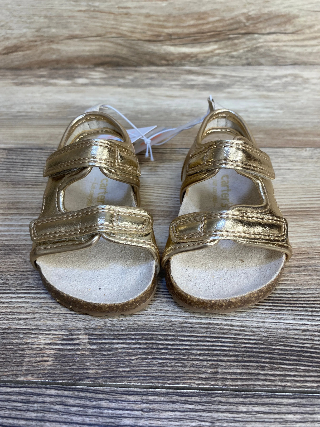 Front view of Just One You First Walker toddler sandals showcasing double Velcro straps and cork footbed on wooden floor