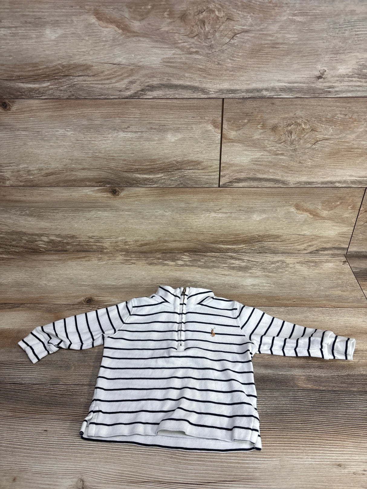 Children's white long sleeve shirt with navy stripes and front zipper, laid on wooden floor