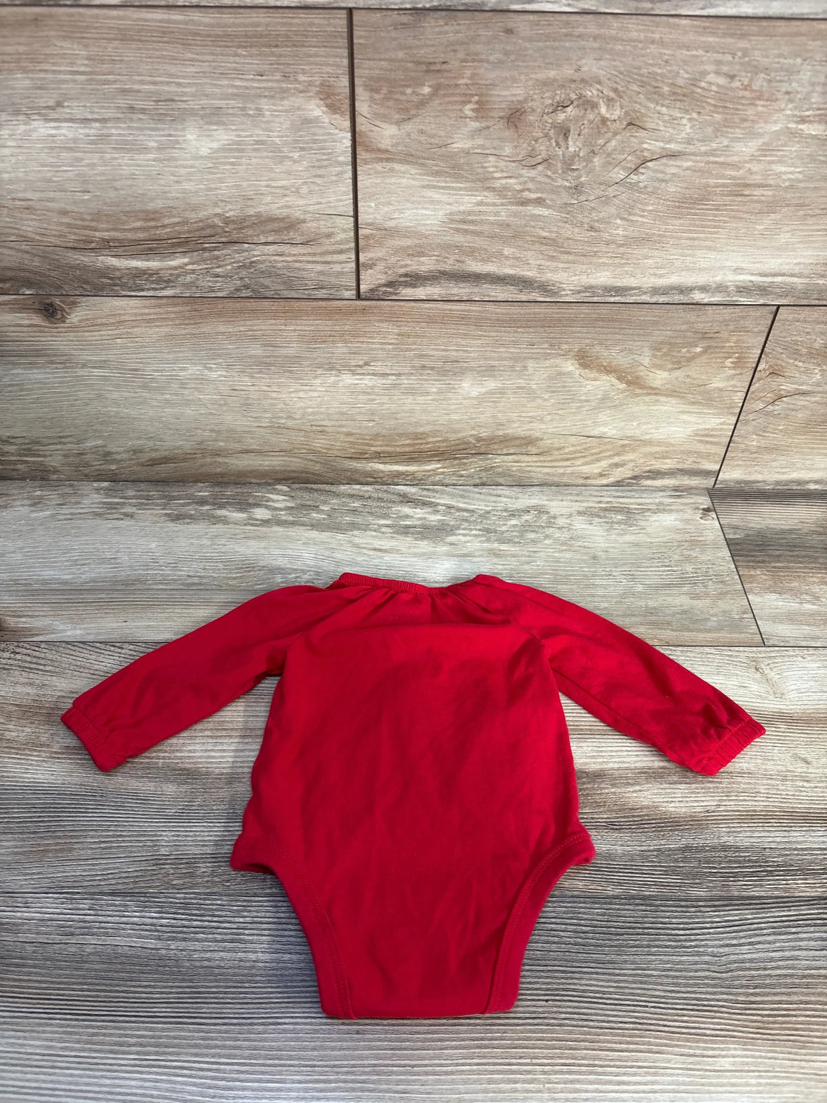 Front view of a red Oshkosh long sleeve henley bodysuit with elastic cuffs on a wood-look floor