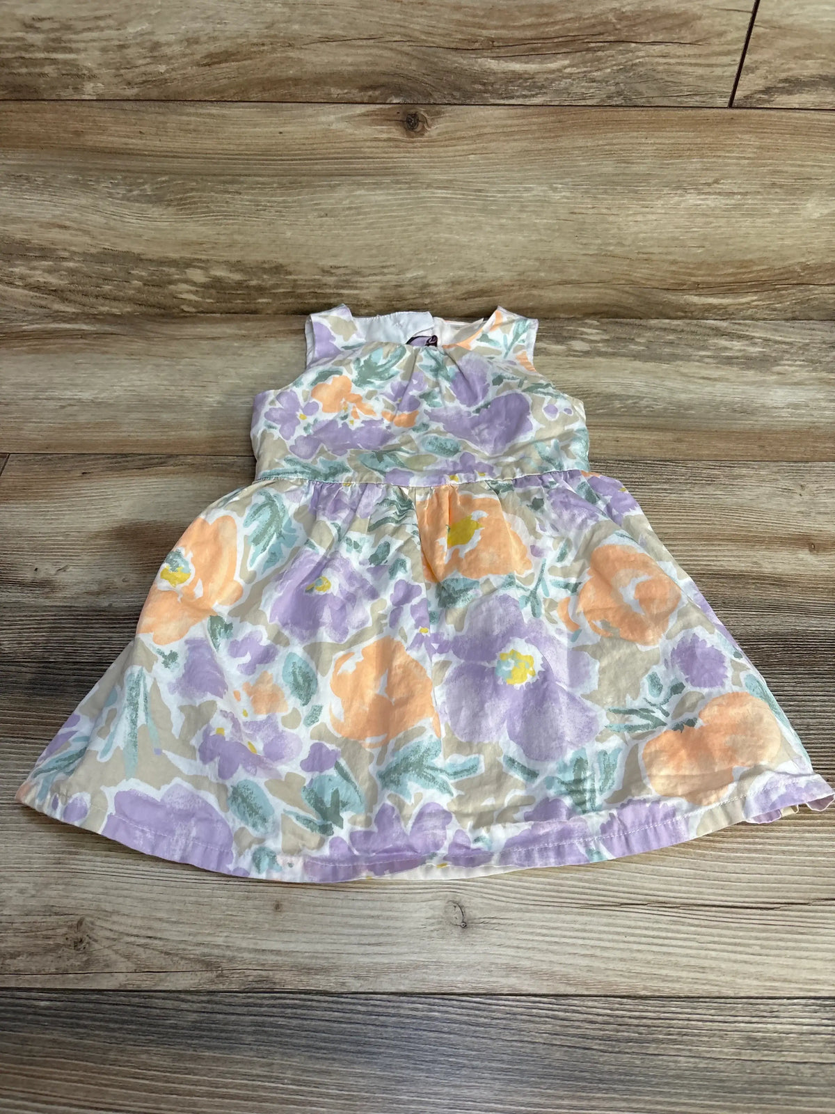 Front flat-lay of Carter's 3T floral dress with pastel orange and lavender flowers on wood background