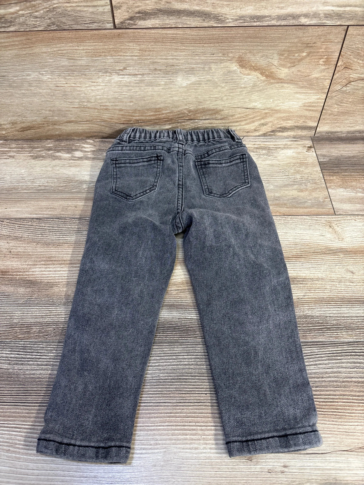Back view of grey toddler jeans size 2T showing elastic waistband and back pockets laid flat on wood surface