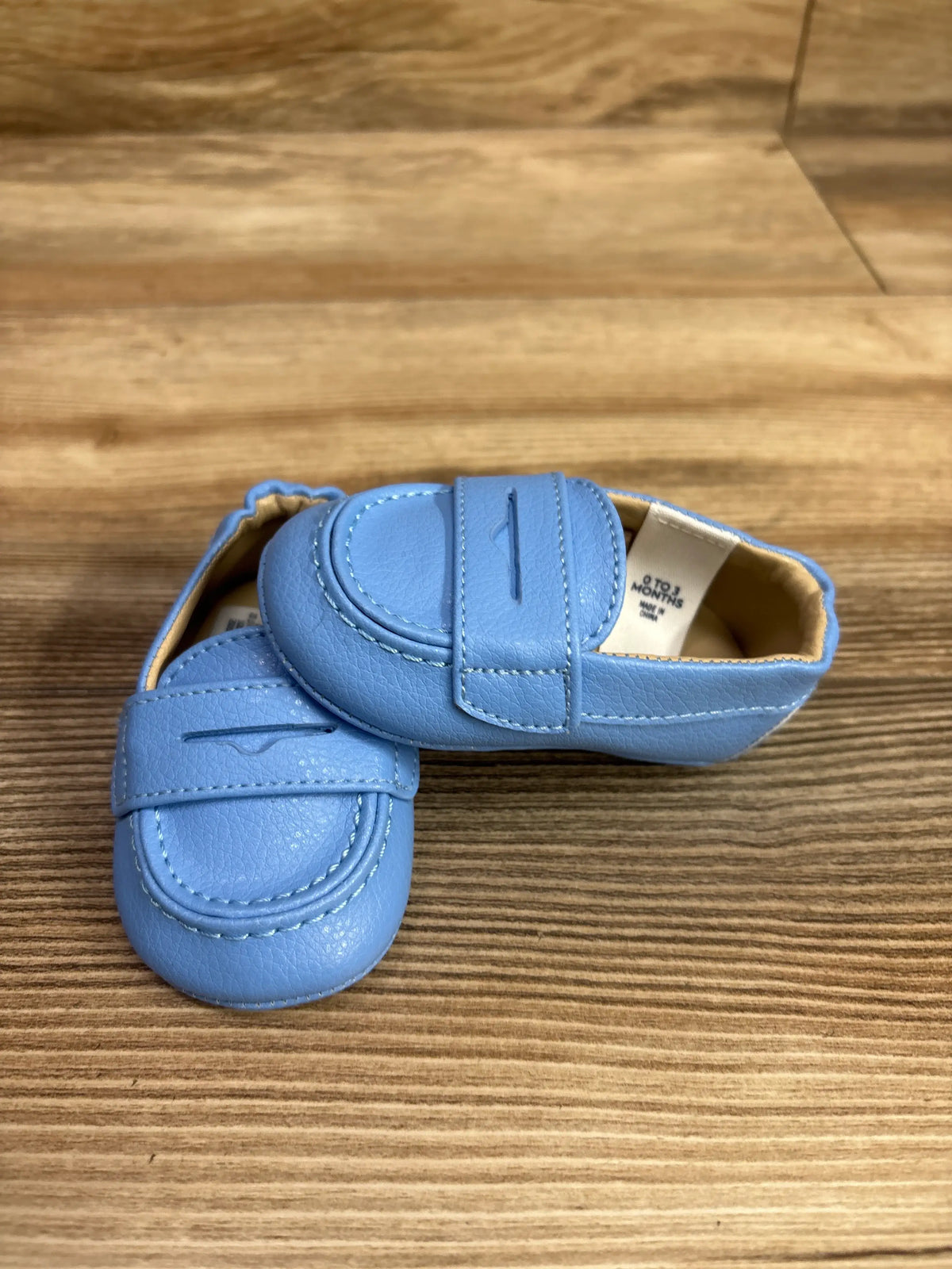 Top view of Janie & Jack blue penny loafer shoes in size 1/2C showcasing penny strap details on a wood surface