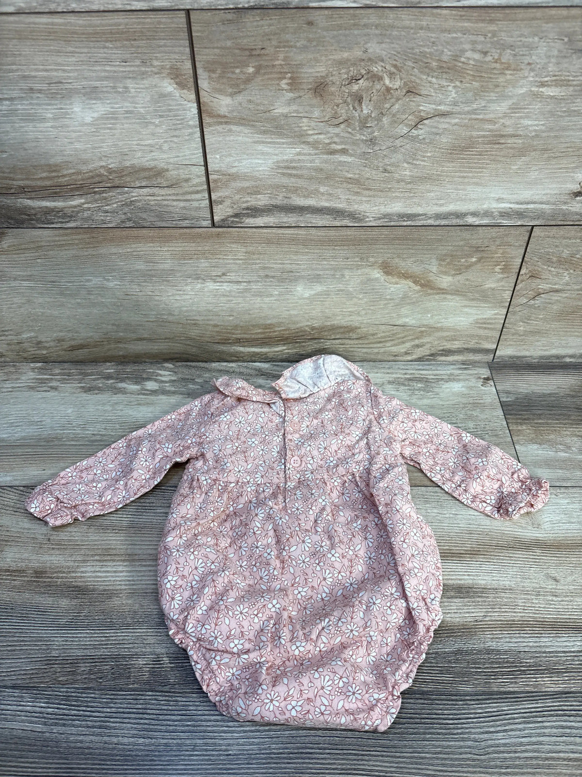 Front view of Just One You floral bubble romper showcasing pink floral print, long sleeves, and bubble hem on wood look background