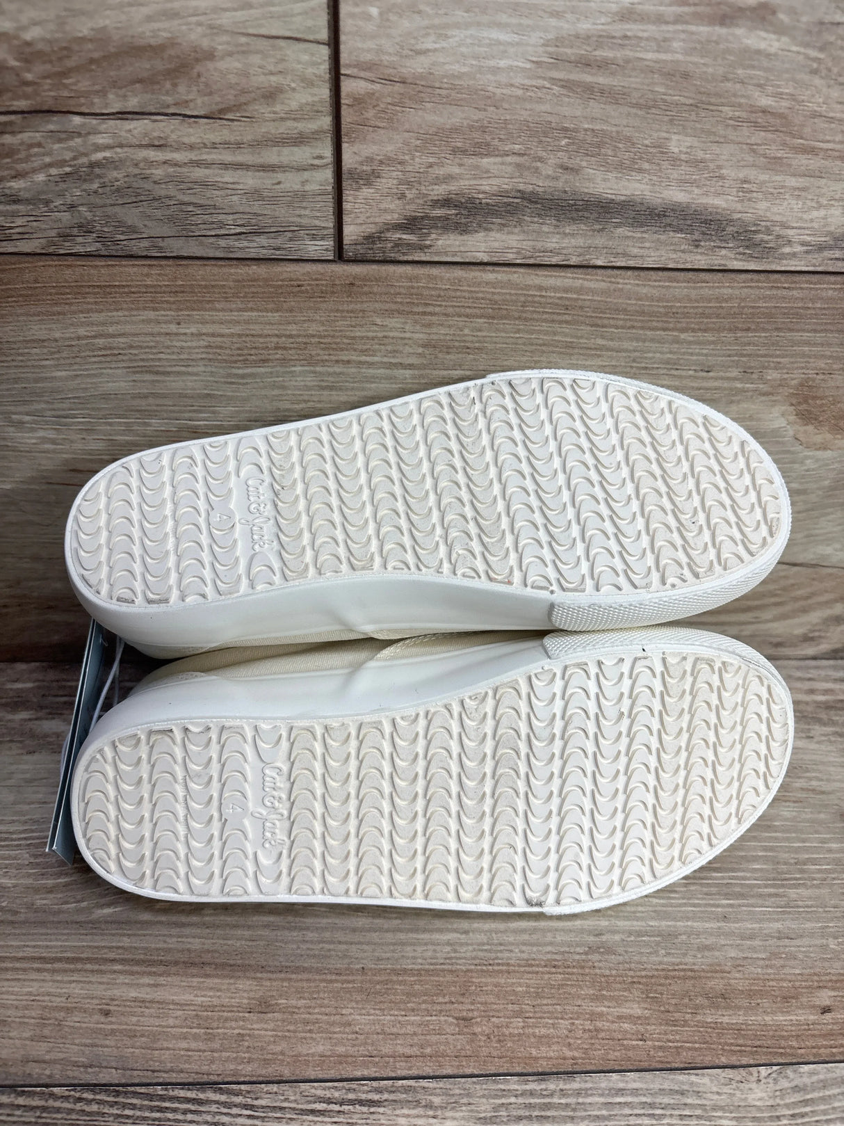 White rubber sole kids shoes with textured tread pattern on wooden floor