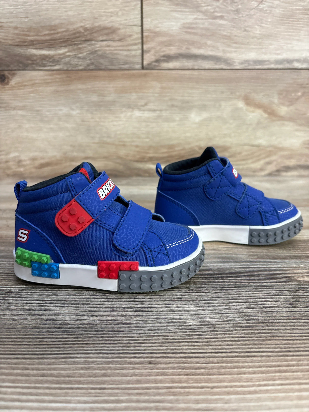 Blue Skechers toddler shoes with LEGO-style brick accents on wood floor