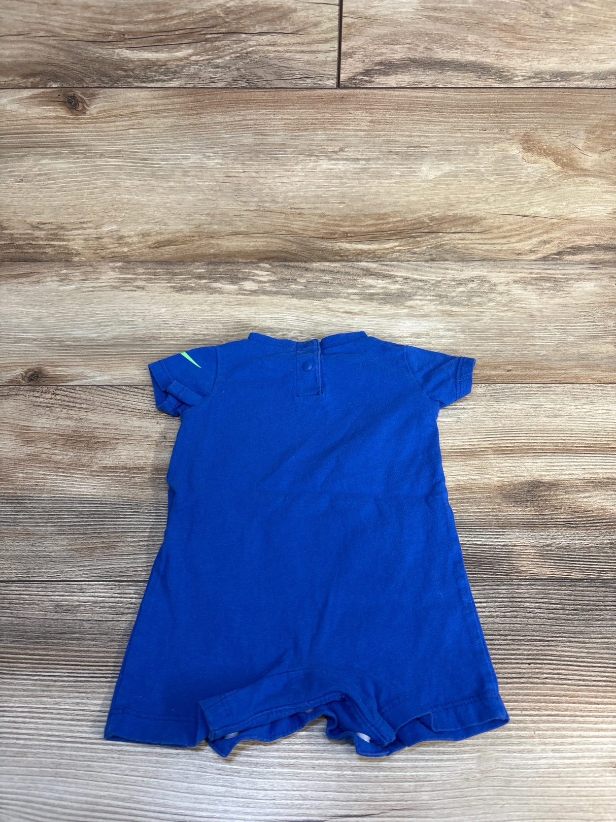 Blue short sleeve baby romper laid flat on wooden background
