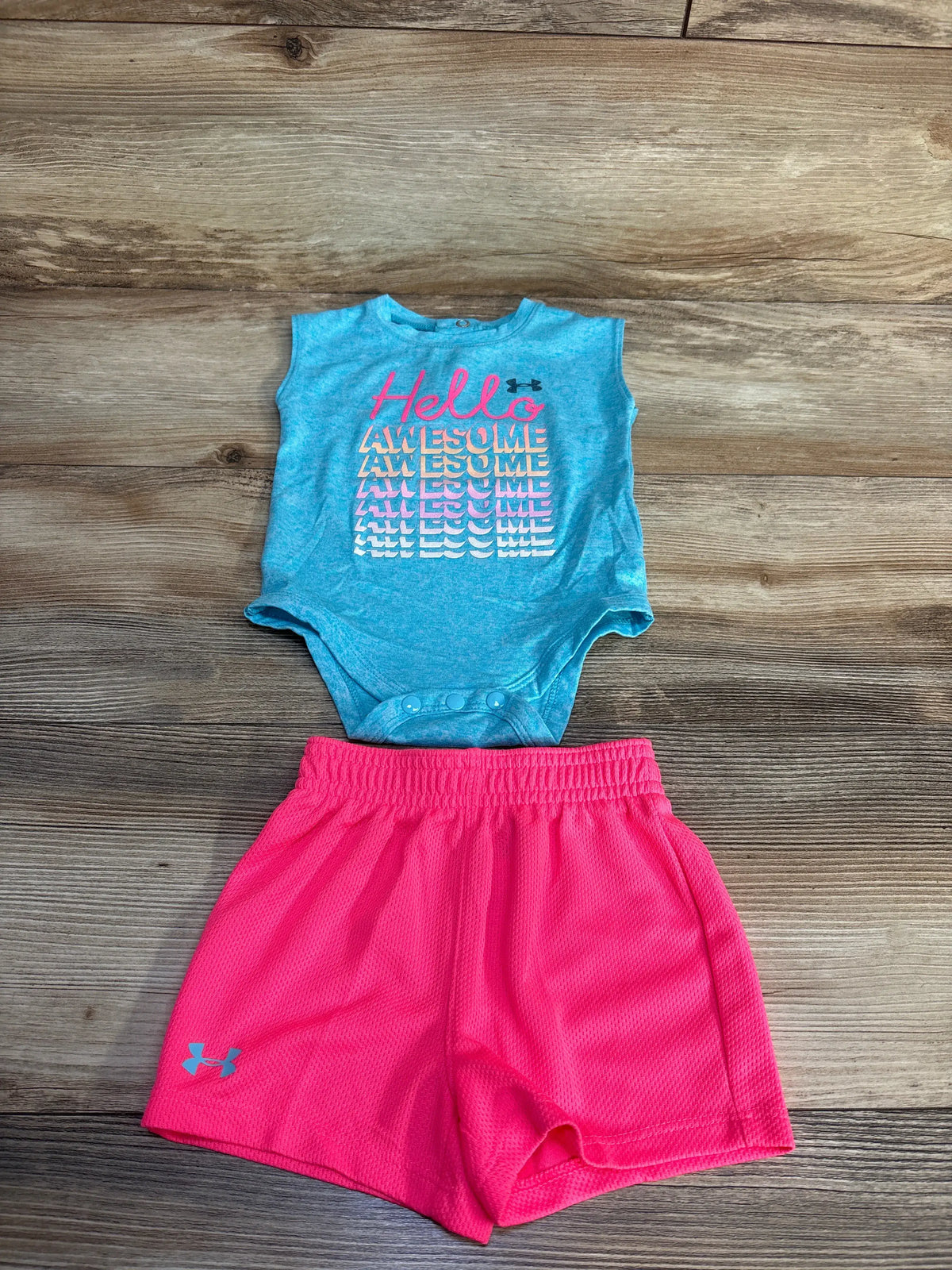 Top view of Under Armour two-piece bodysuit and shorts set showcasing a graphic bodysuit on a wood floor