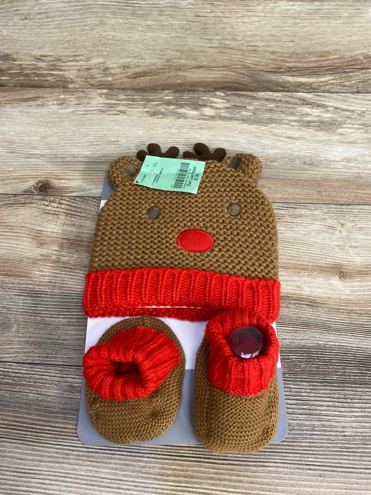 Brown and red knitted baby reindeer hat with matching booties on wooden surface