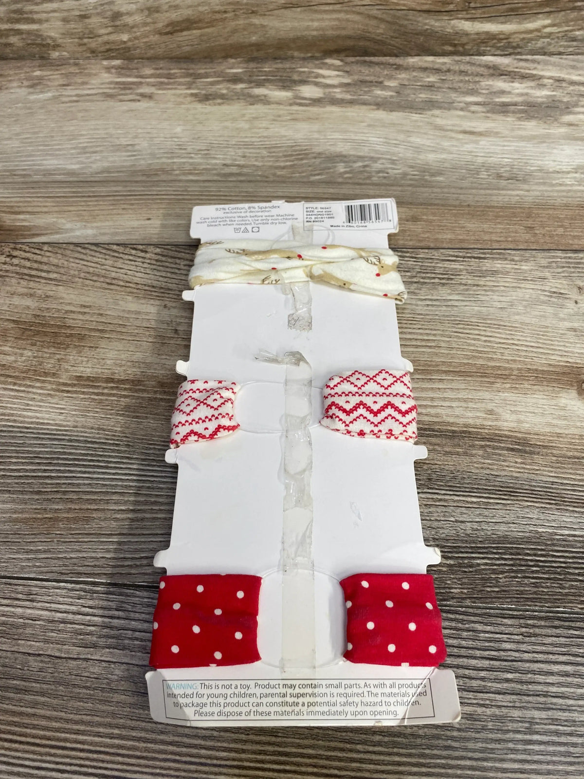 Set of three festive fabric headbands with reindeer, red and white patterns, and polka dots on wooden surface