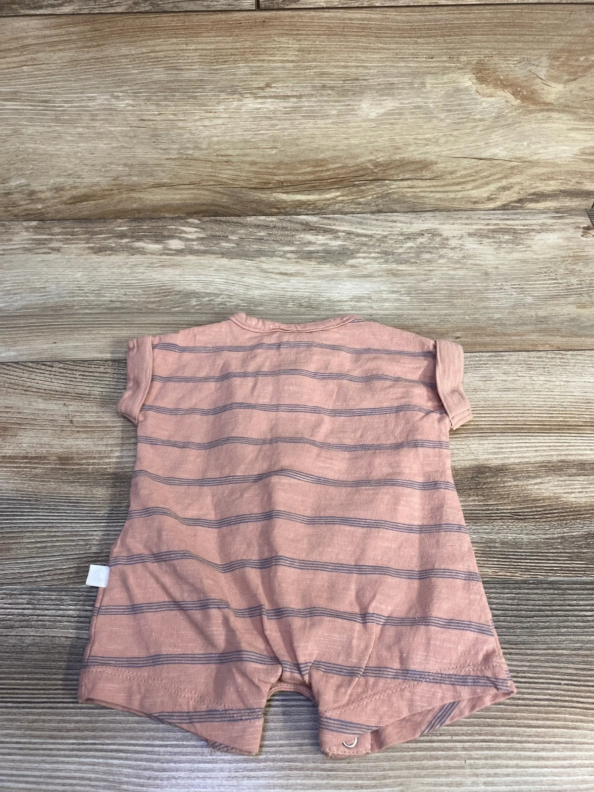 Back view of Little Planet organic striped shortie romper in muted orange showing navy horizontal stripes and snap crotch on wood background