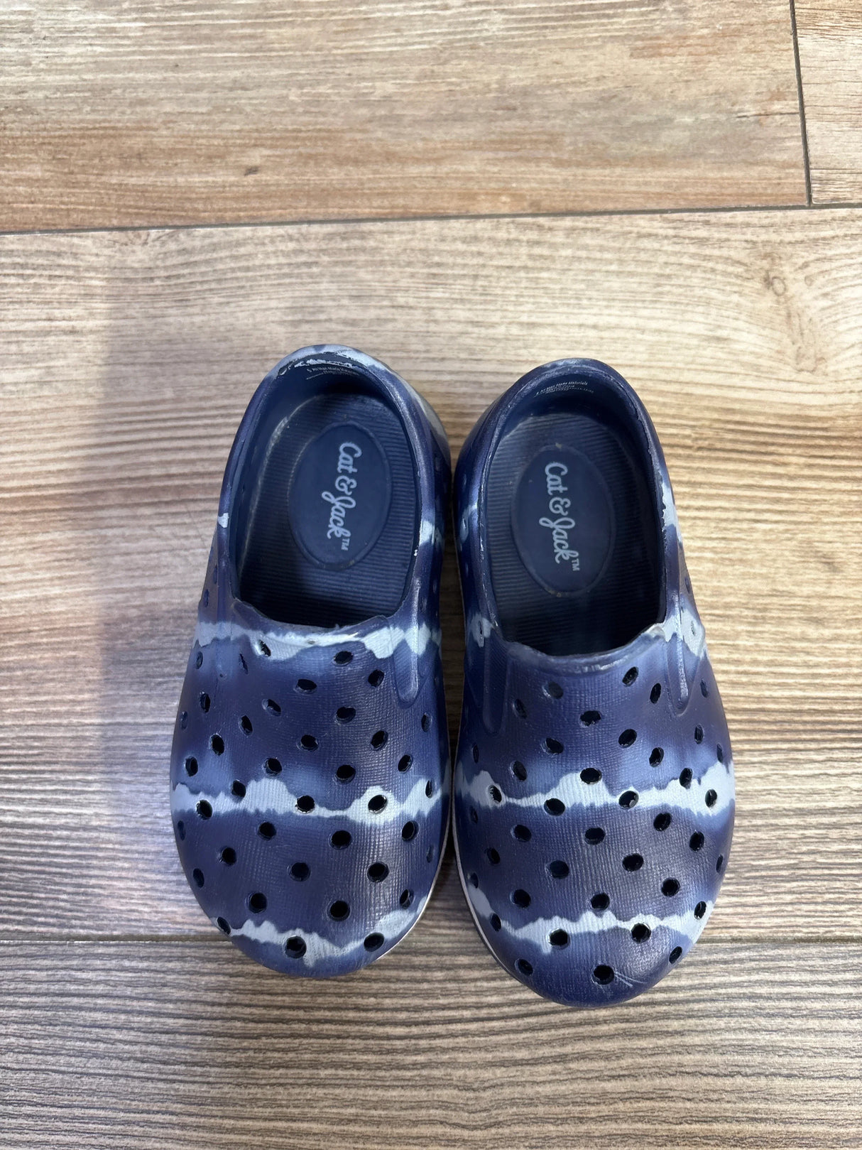 Top view of Cat and Jack slip-on toddler water shoes size 5C showing blue tie-dye pattern, perforated upper and molded footbed on wood floor