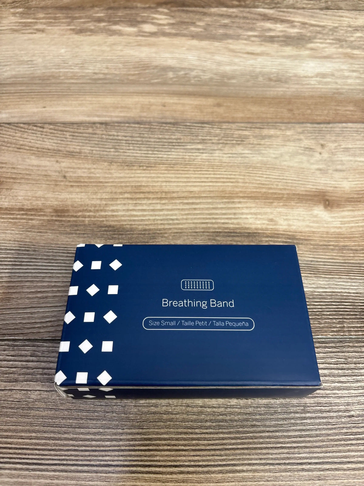 Blue box of Small size Breathing Band with white geometric pattern on a wooden surface