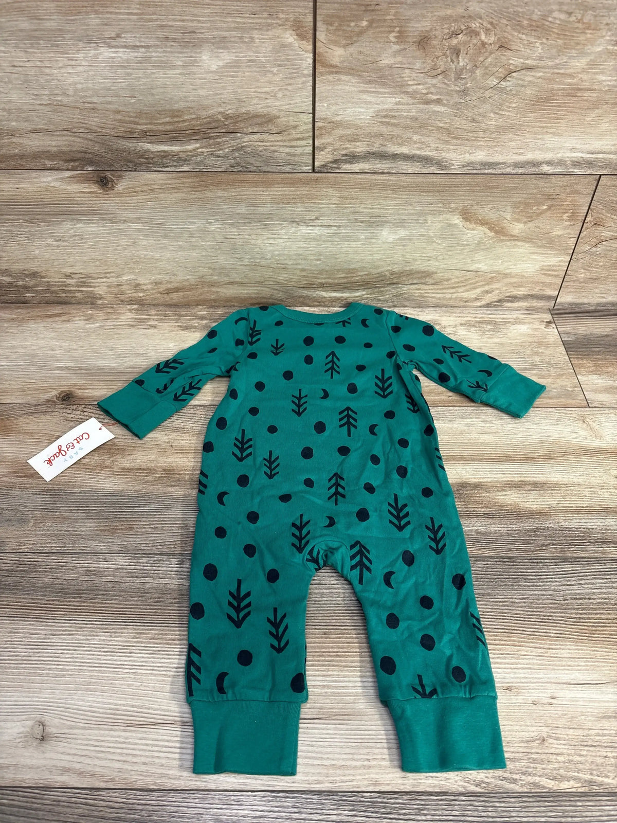 Teal baby romper with black tree and dot pattern, long sleeves, displayed on wood floor