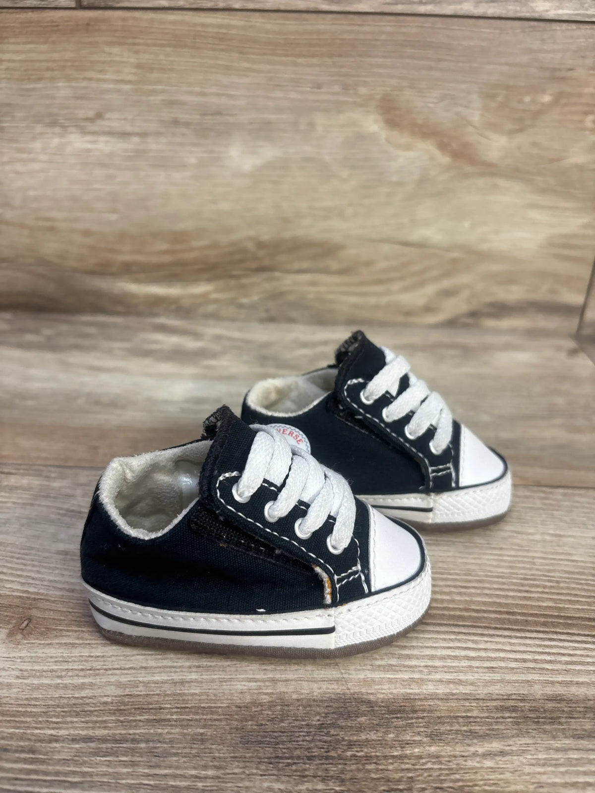 Three-quarter view of black canvas Converse All Star Cribster Easy-On shoes with white toe caps on a wood floor