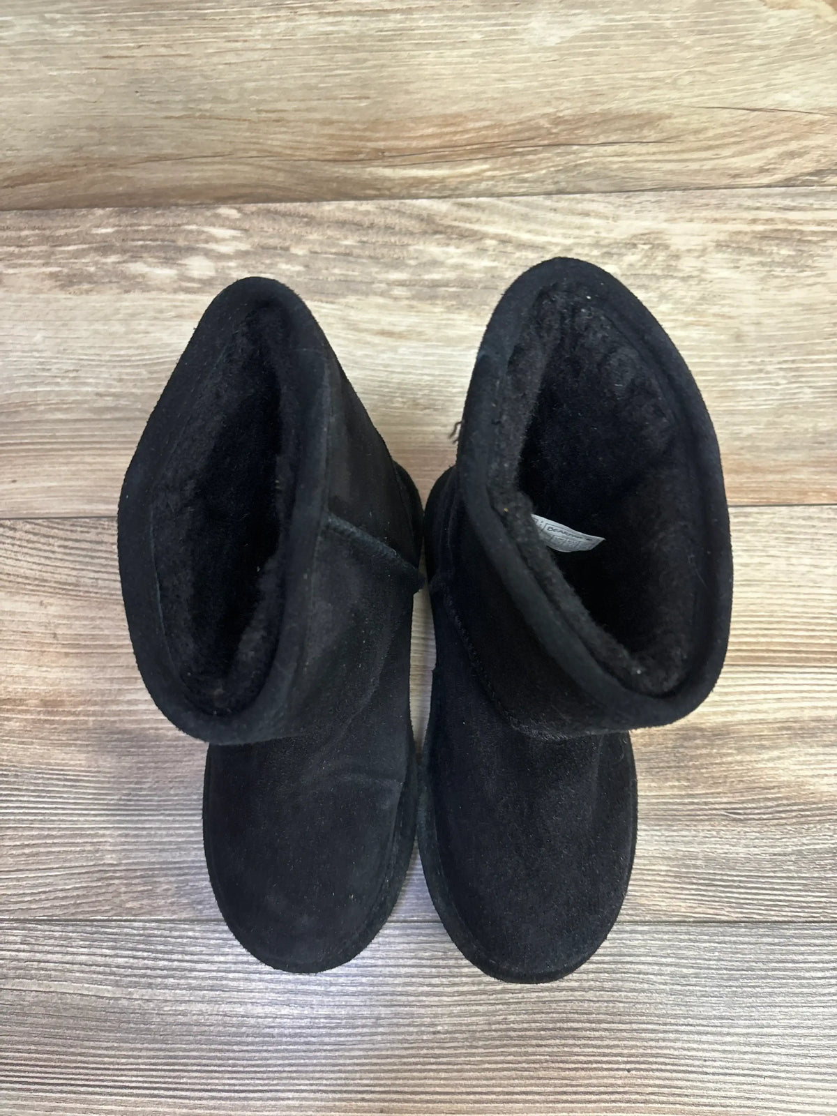 Pair of black toddler winter boots with soft lining on wood floor background