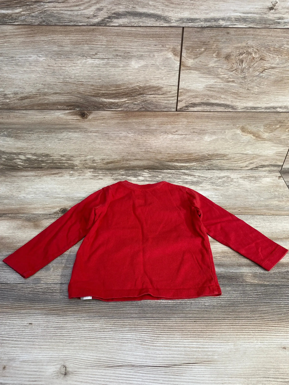 Back view of Baby Gap shirt showcasing solid red long sleeve knit on wood plank floor