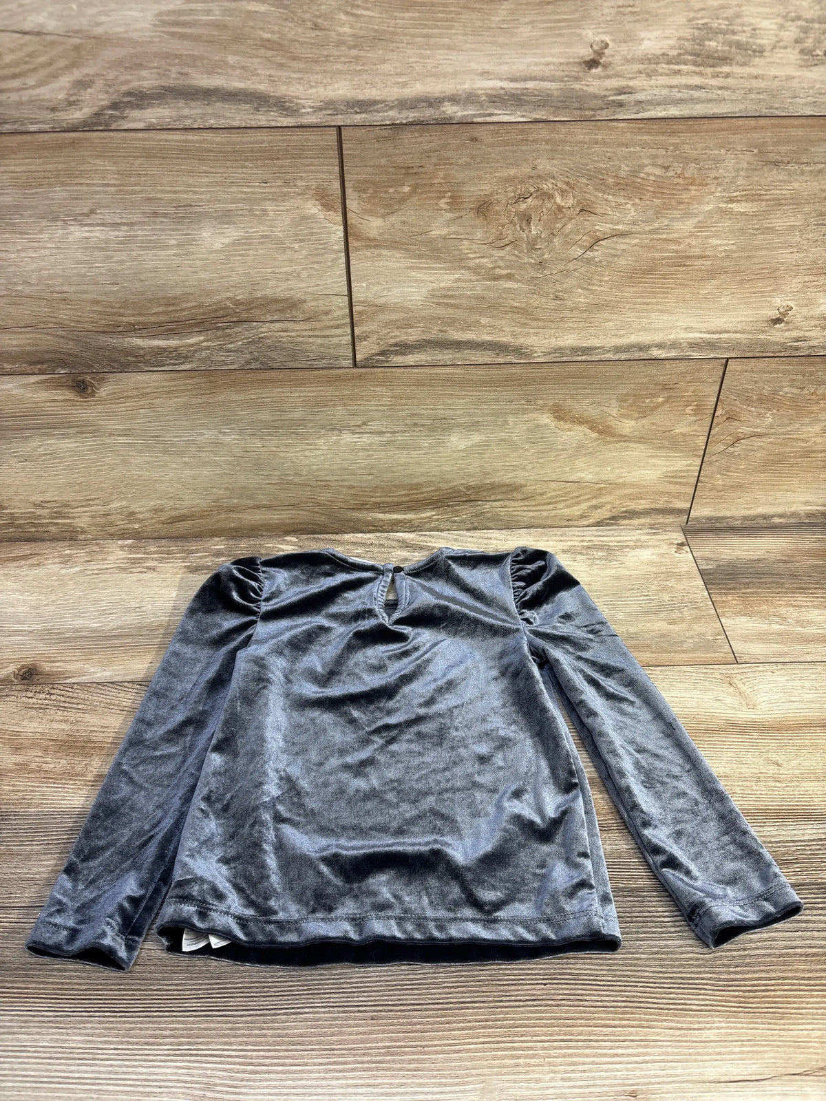 Front view of Baby Gap grey velvet shirt showcasing puff sleeves and keyhole neckline on a wood floor