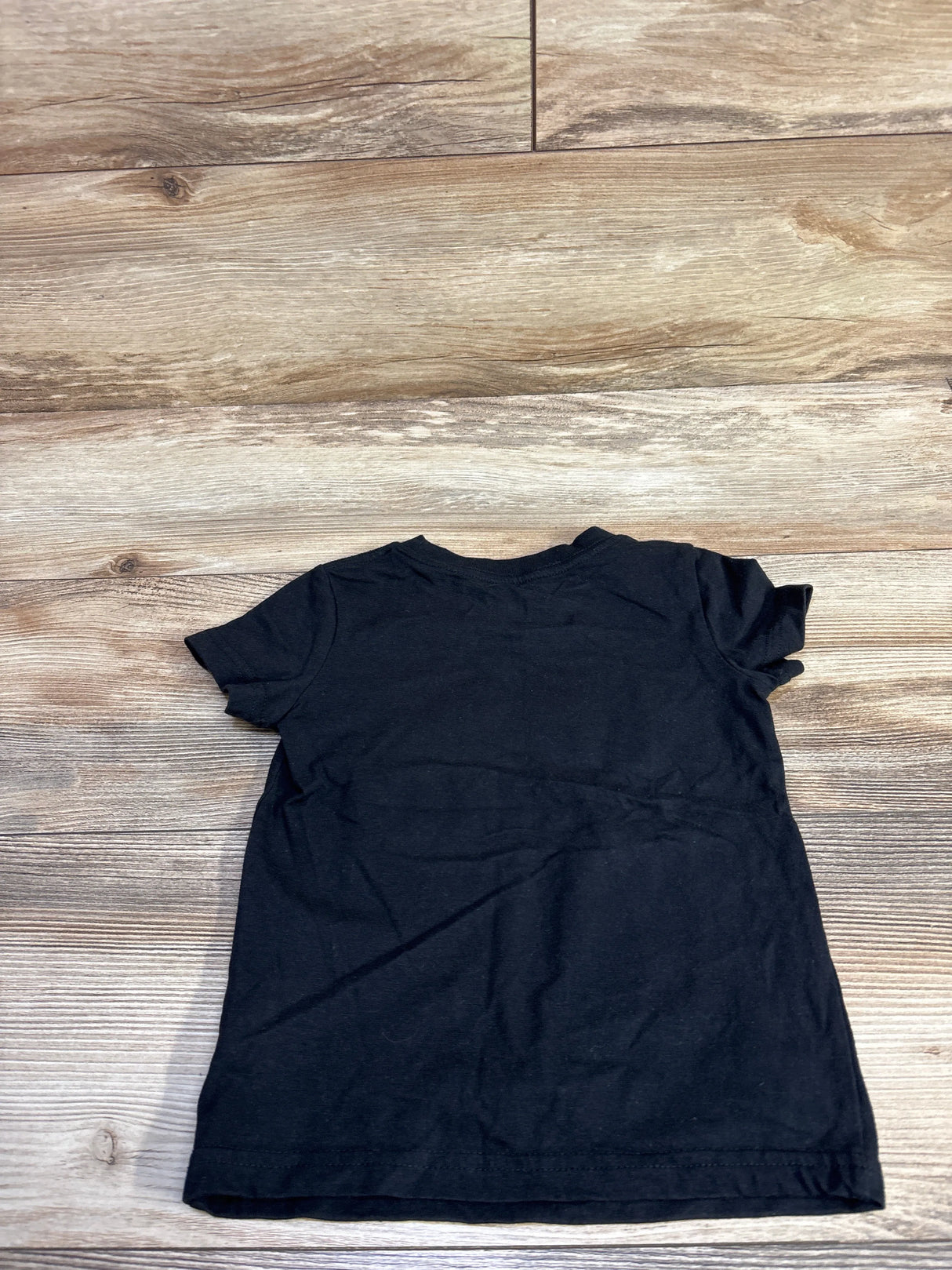 Back view of Cat and Jack Strong black toddler t-shirt, size 2T, short sleeves and crew neck on wood floor background