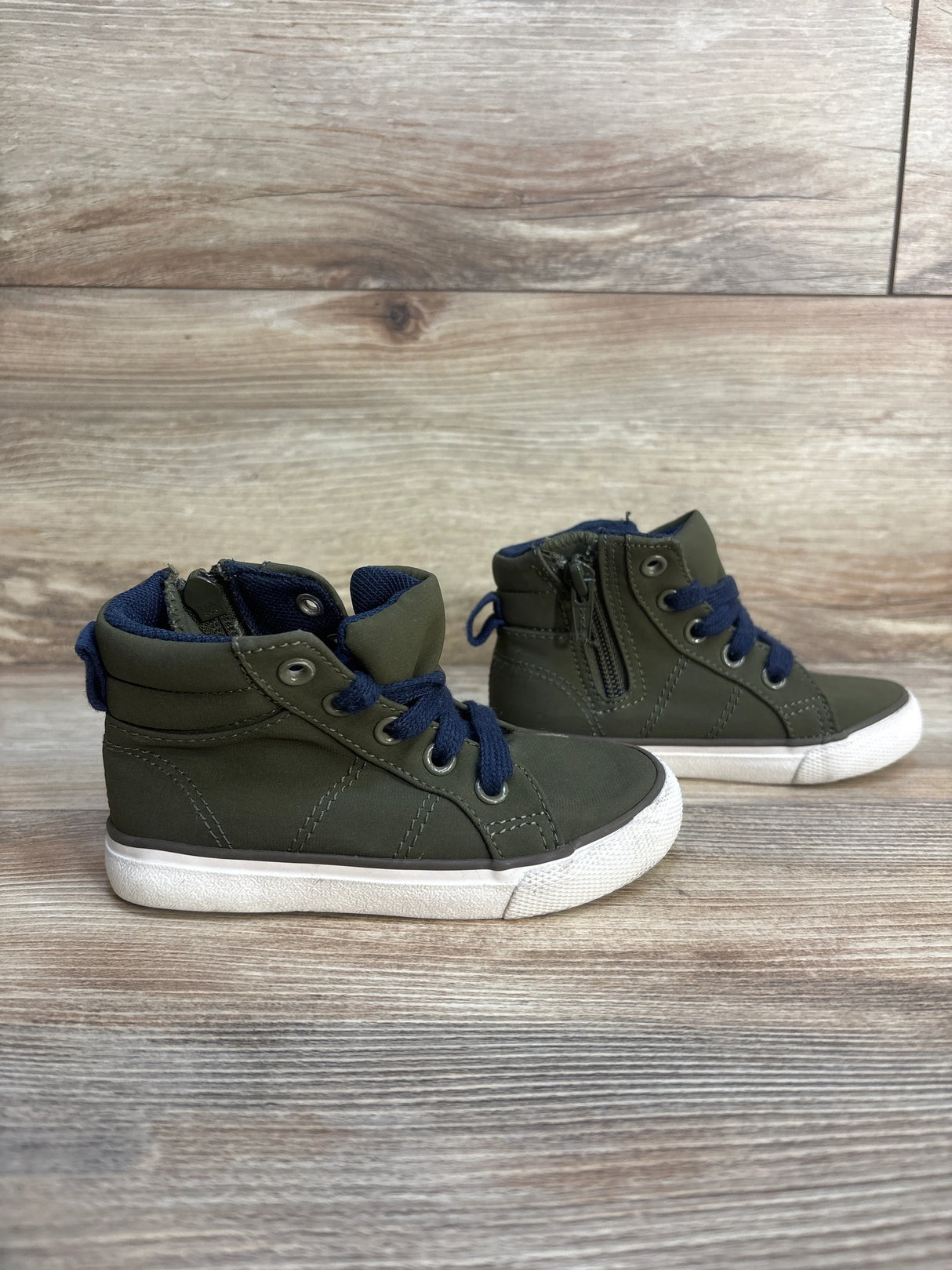 Olive green toddler high-top sneakers with navy laces on wood background
