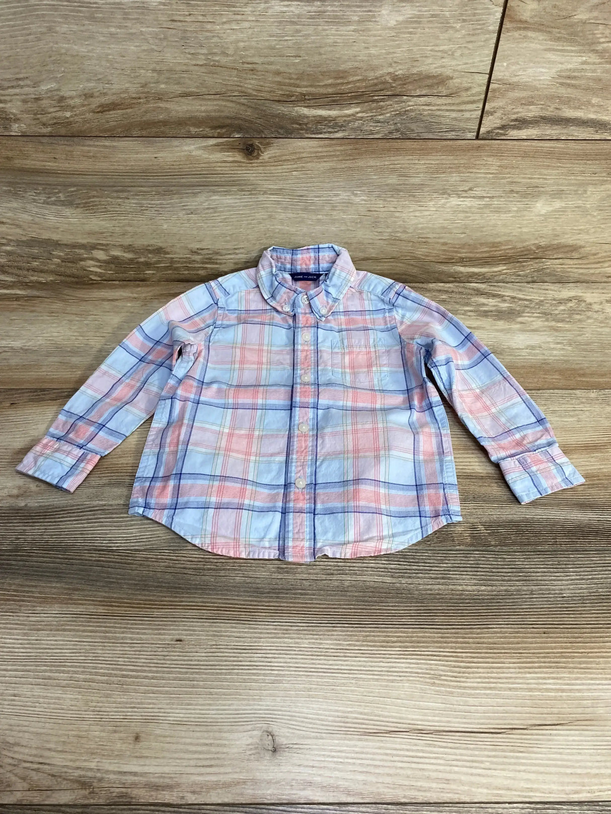 Flat lay of Janie and Jack plaid button down shirt showcasing pink blue and white check with button down collar and chest pocket on wood plank floor