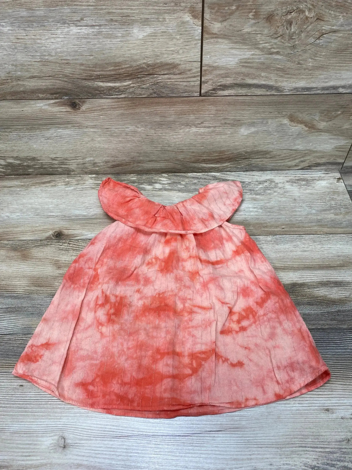 Flat lay of Splendid tie-dye toddler dress with coral-pink ruffle neckline, A-line shape, size 18-24 months on wood background