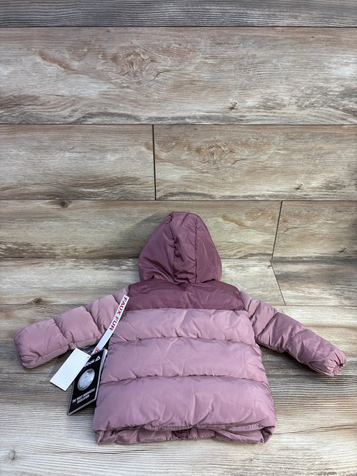Back view of Reebok hooded heavyweight puffer jacket in dusty rose, size 12m, with hood on wood floor