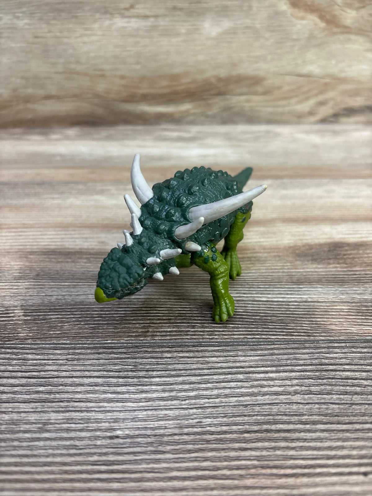 Angled view of Mattel Sauropelta dinosaur figure showcasing green armor and white spikes on a wood surface