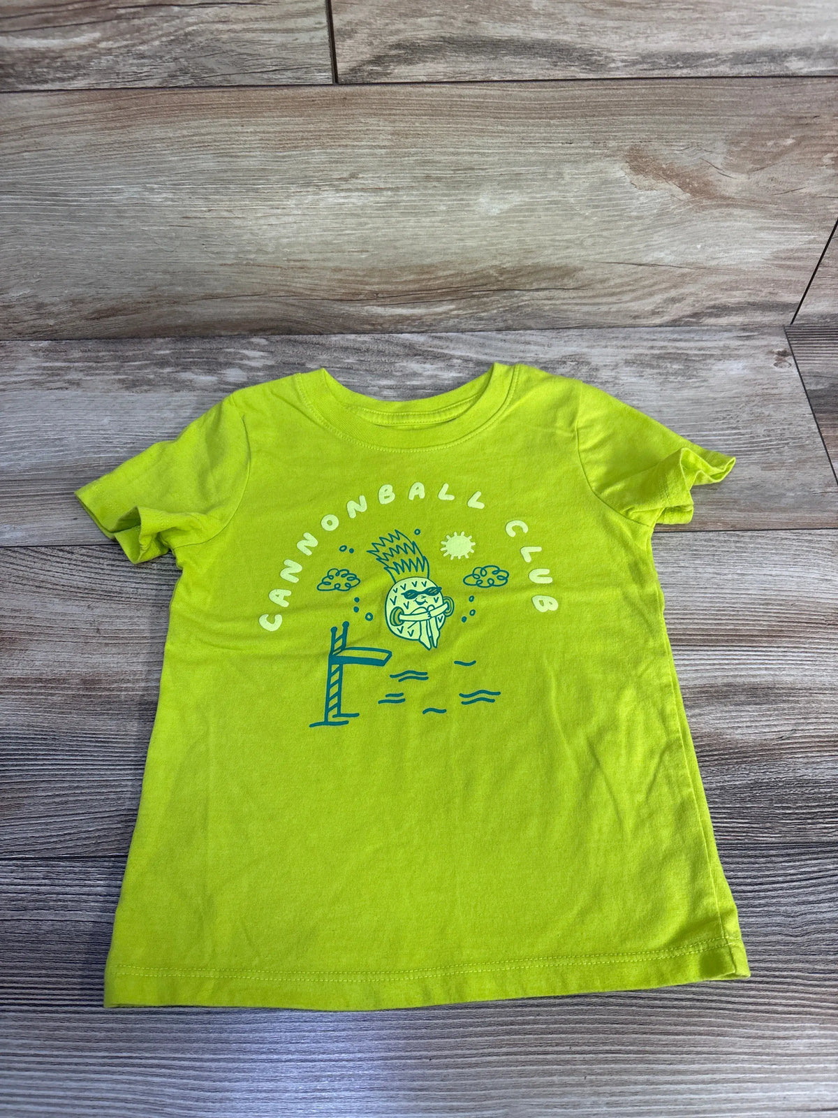 Front view of Cat & Jack toddler shirt in lime green showcasing the Cannonball Club diving graphic with a gray wood background