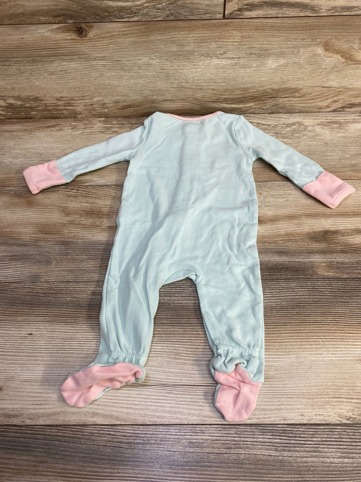Light blue baby onesie with pink cuffs and footies on wooden floor