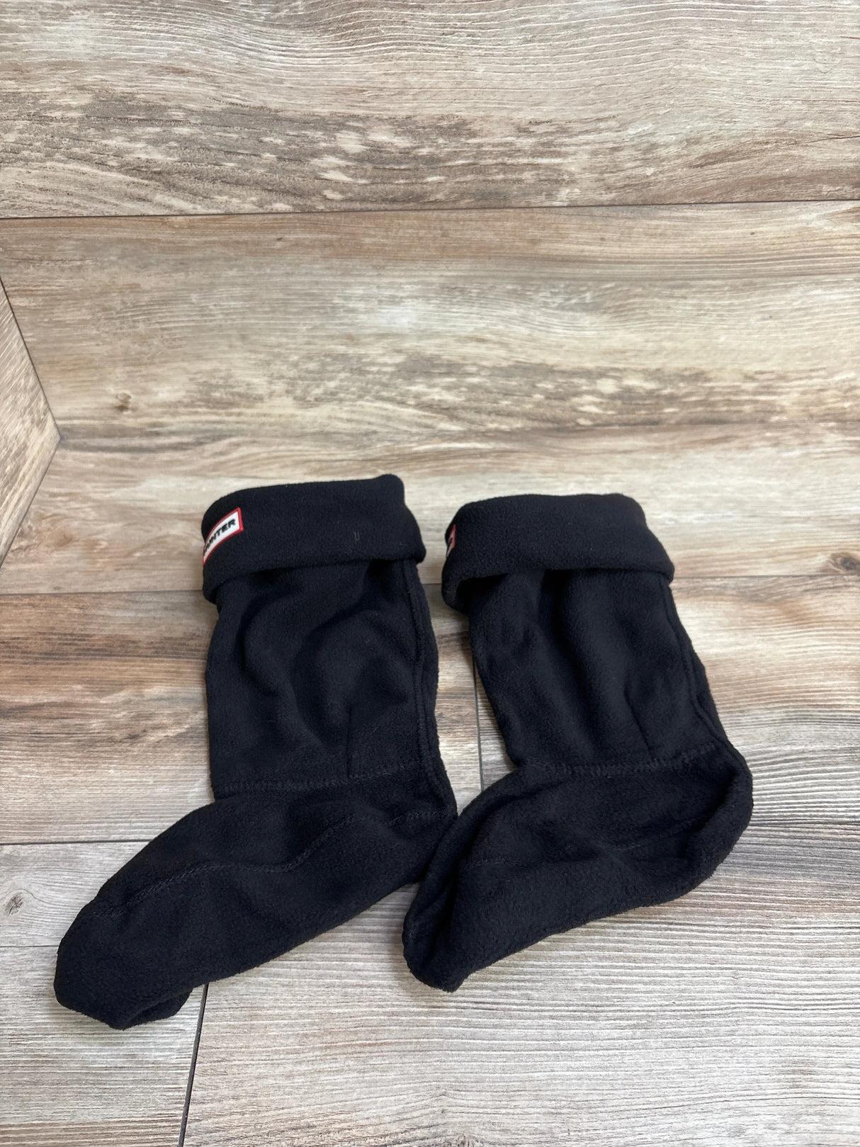 Pair of black fleece boot socks for kids on wood background