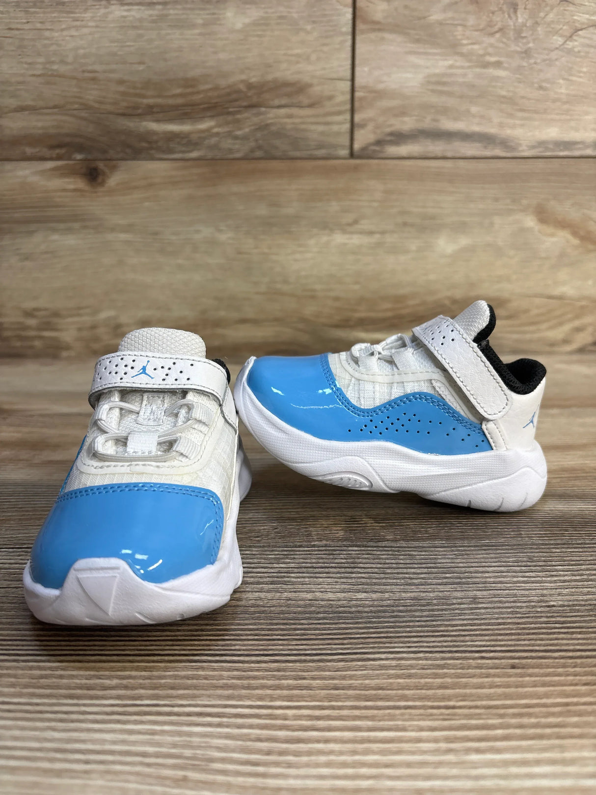 Toddler sneakers with white mesh and blue patent accents on wood background