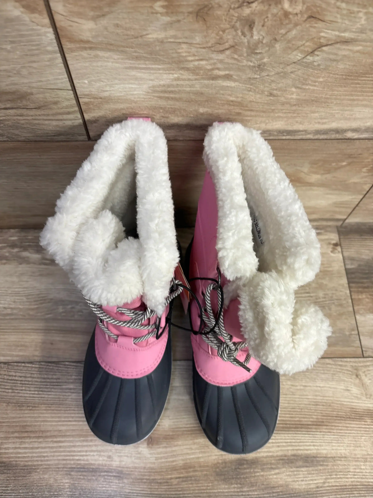 Pink and black kids winter snow boots with faux fur lining on wood floor
