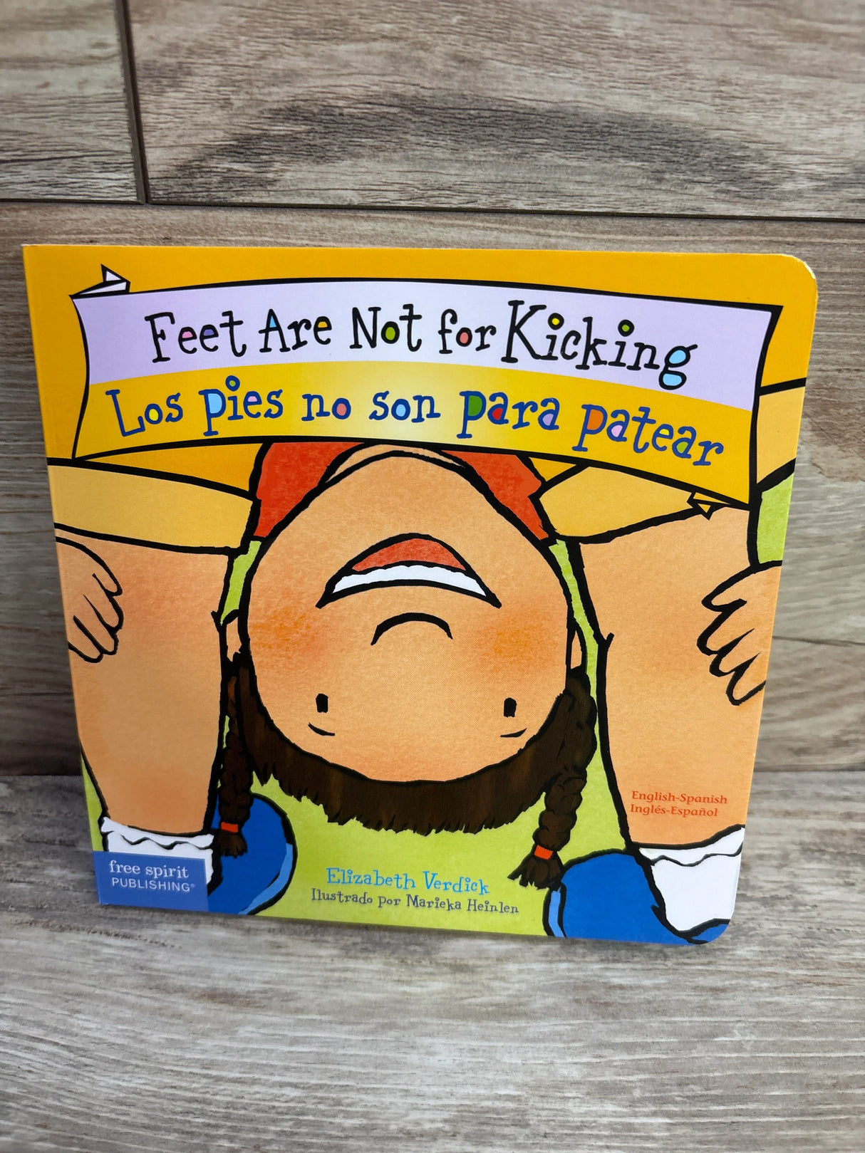 Feet Are Not for Kicking bilingual board book cover, child illustration, wood background