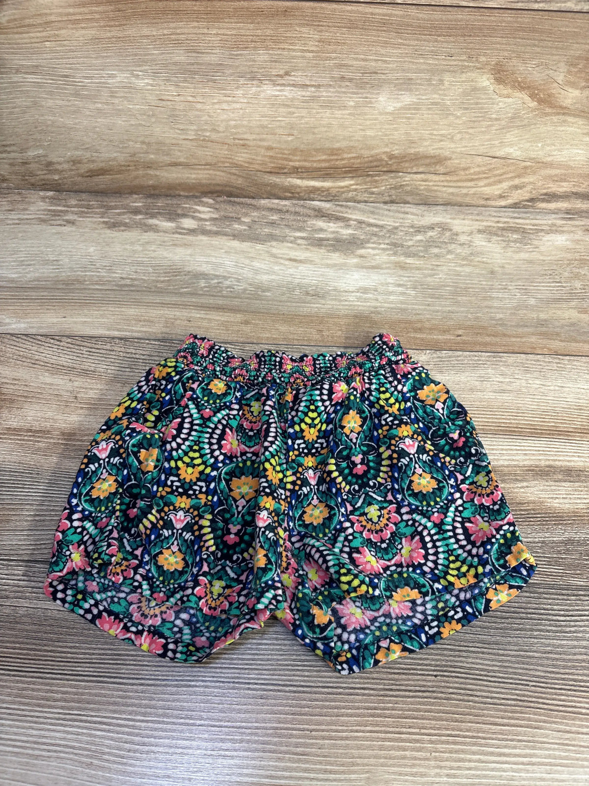 Front view of Old Navy rayon pattern shorts showcasing floral print and elastic waist on a wood background