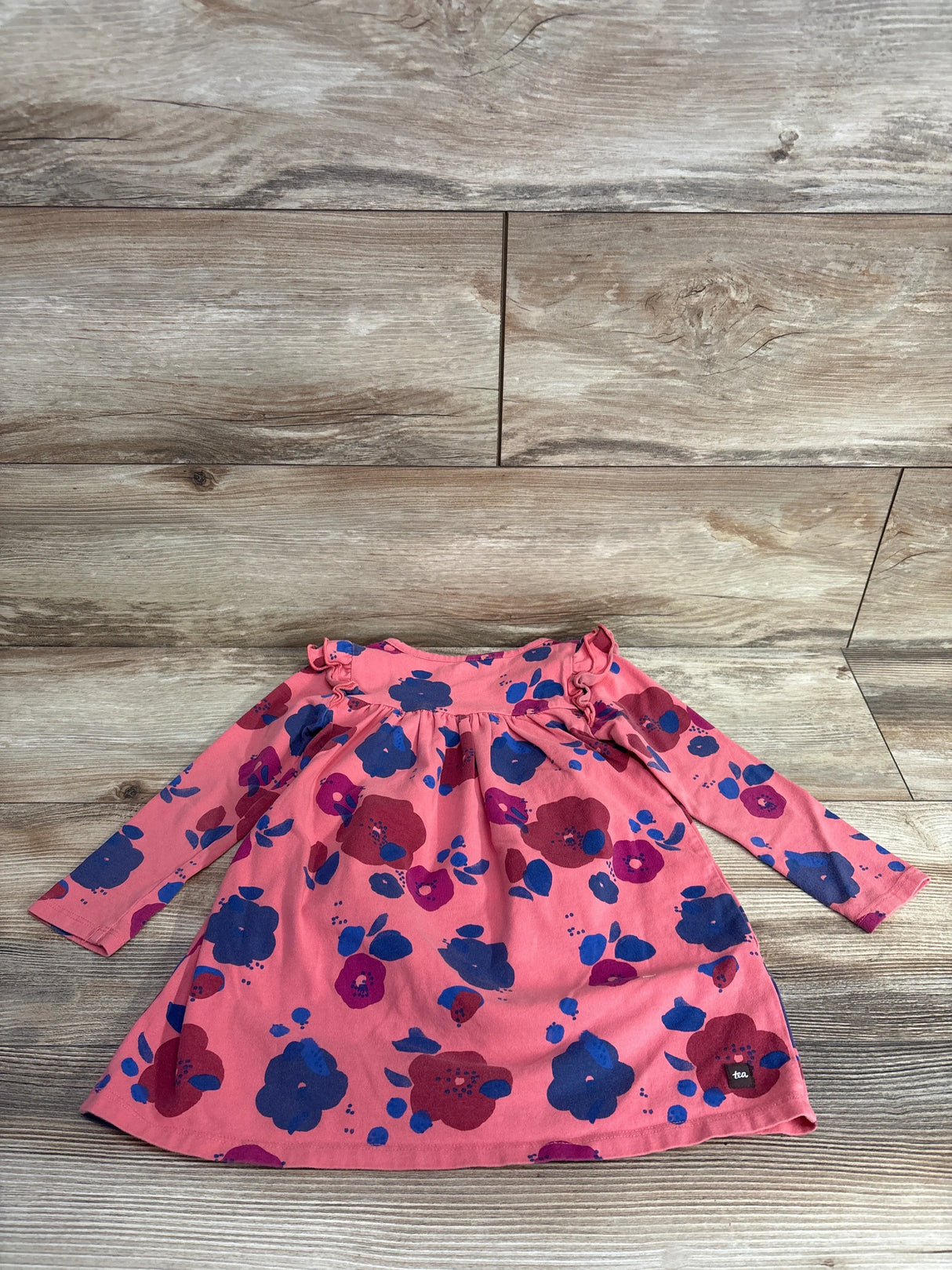 Pink long sleeve girls floral dress with purple and blue flowers on wood background