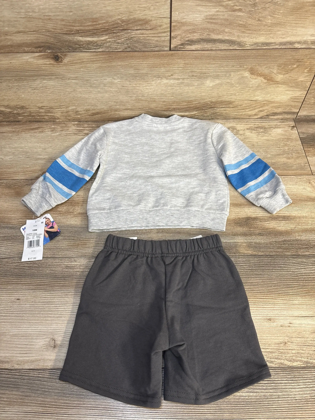 Gray long sleeve toddler shirt with blue sleeve stripes and black shorts set on wood floor