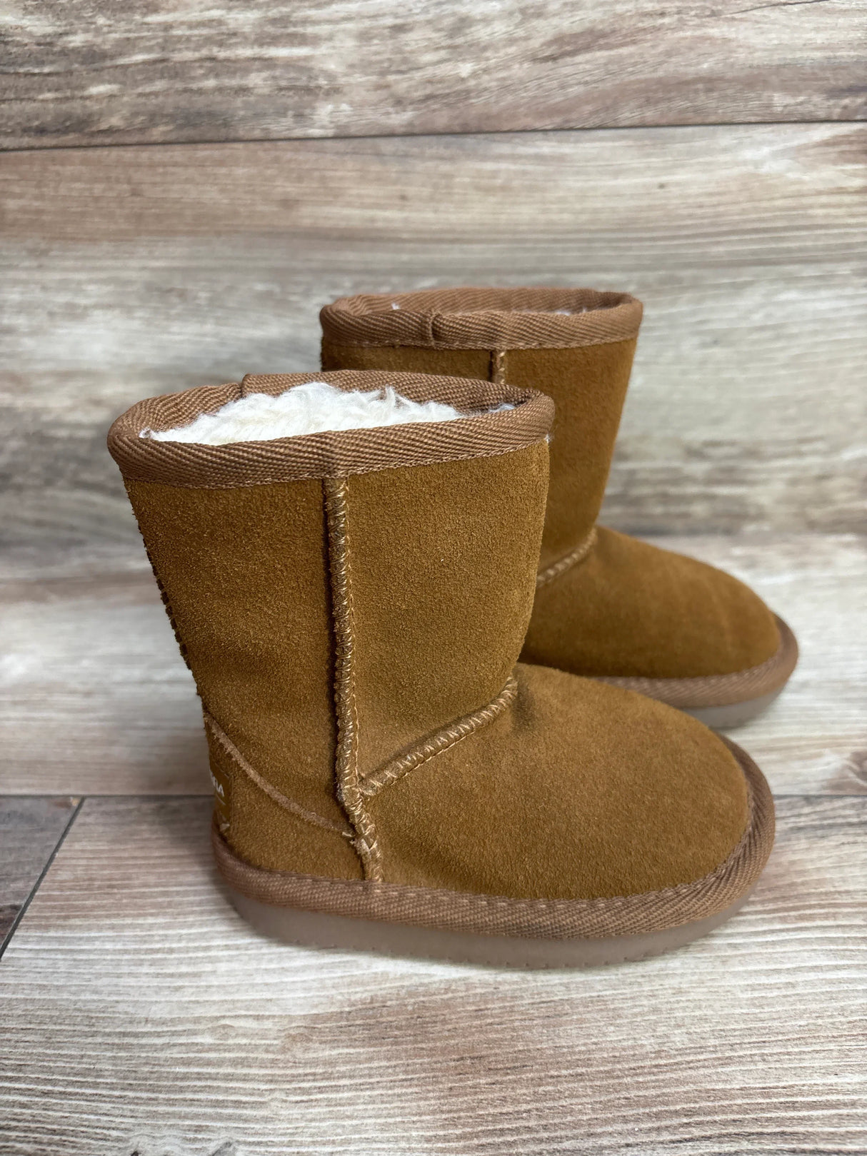 Pair of brown toddler winter boots with soft wool lining on wooden floor