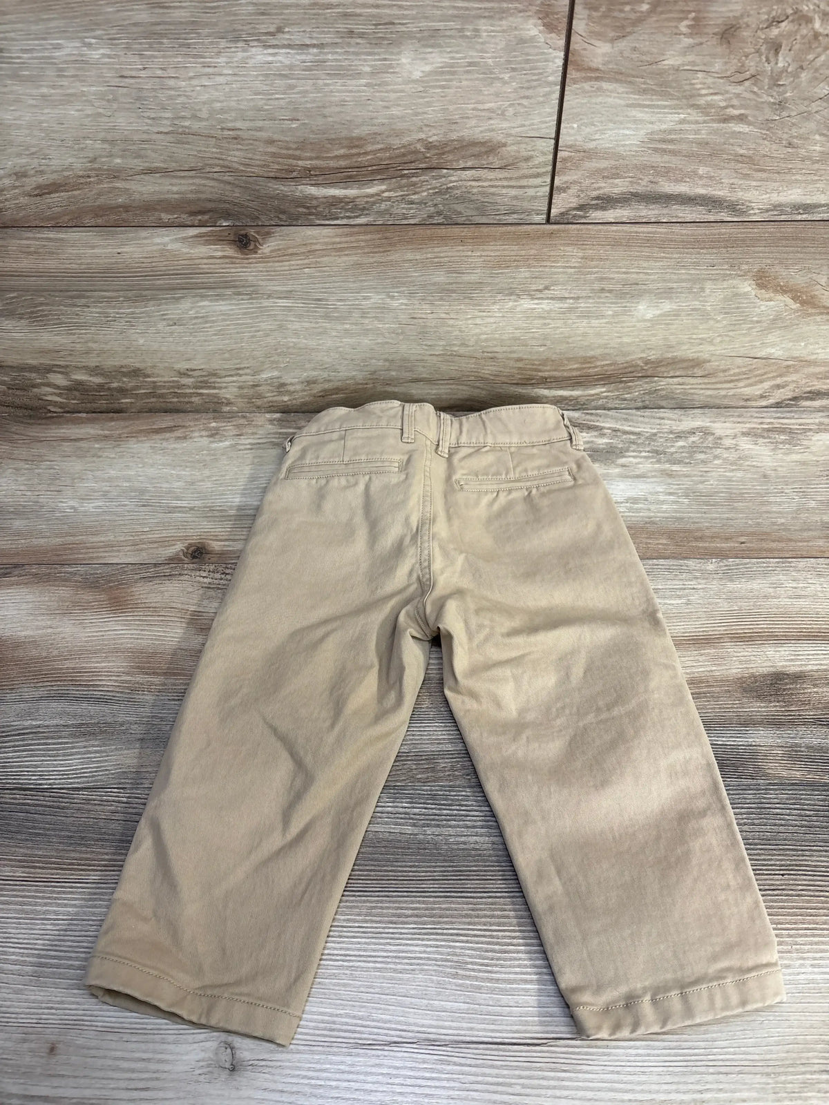 Back view of Baby Gap slim chino pants in khaki, size 2T, showing elasticized waist and back welt pockets on wood floor